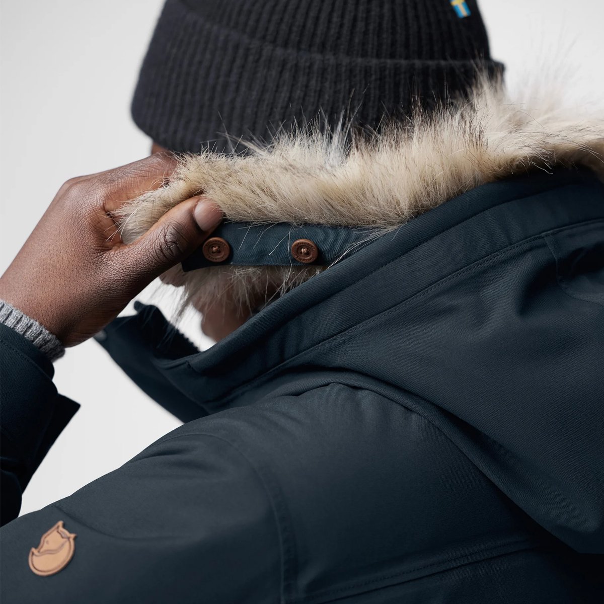 A man detaches the protective hood from the Fjallraven Nuuk Lite parka.