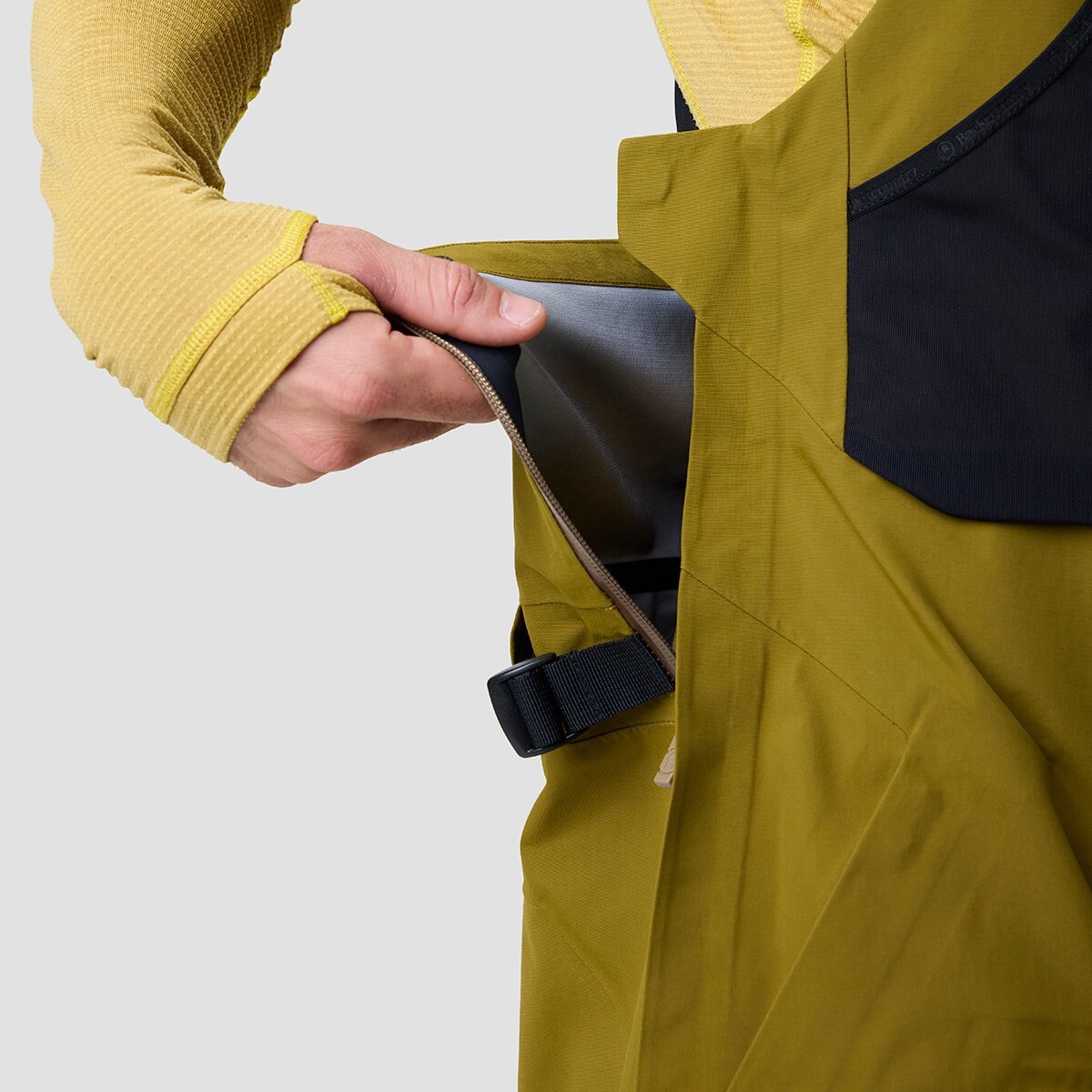 Person wearing Cottonwoods ski bib unzipping drop seat side zipper.
