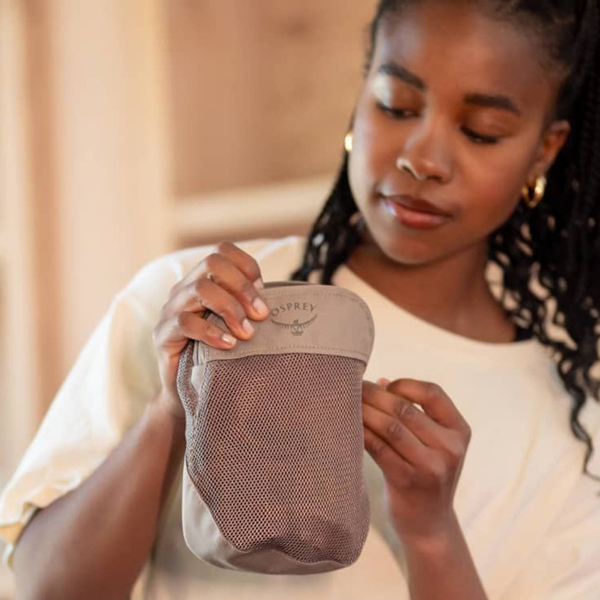 A woman holds an Osprey Daylite packing cube accessory. 