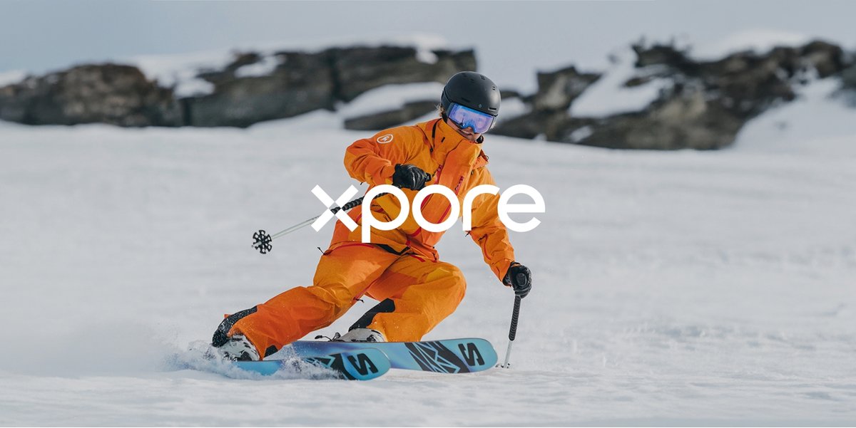 The Xpore logo overlaid on an image of a skier in an orange Cottonwoods LT kit carving. 