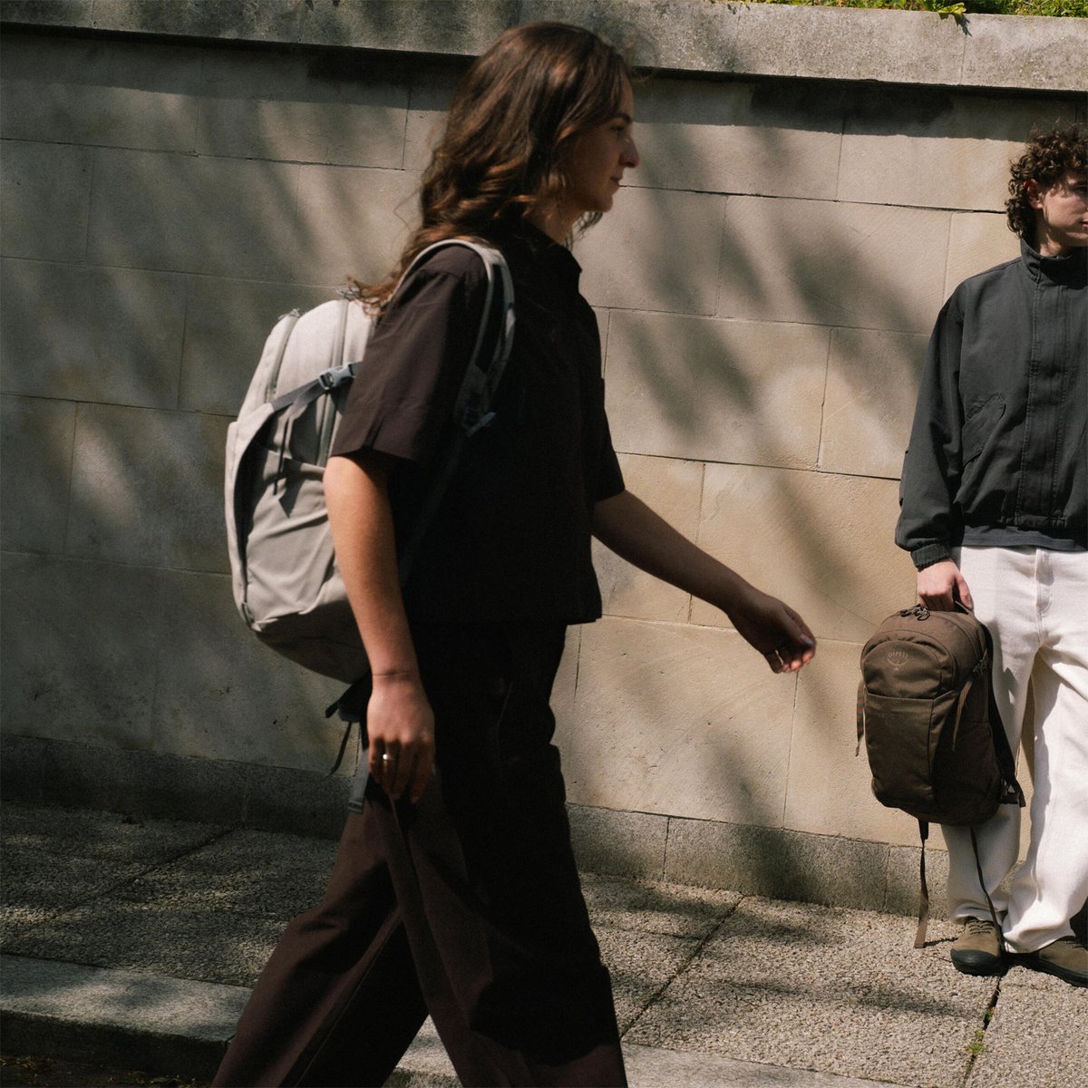 A woman wearing an Osprey Daylite backpack walks down the street.