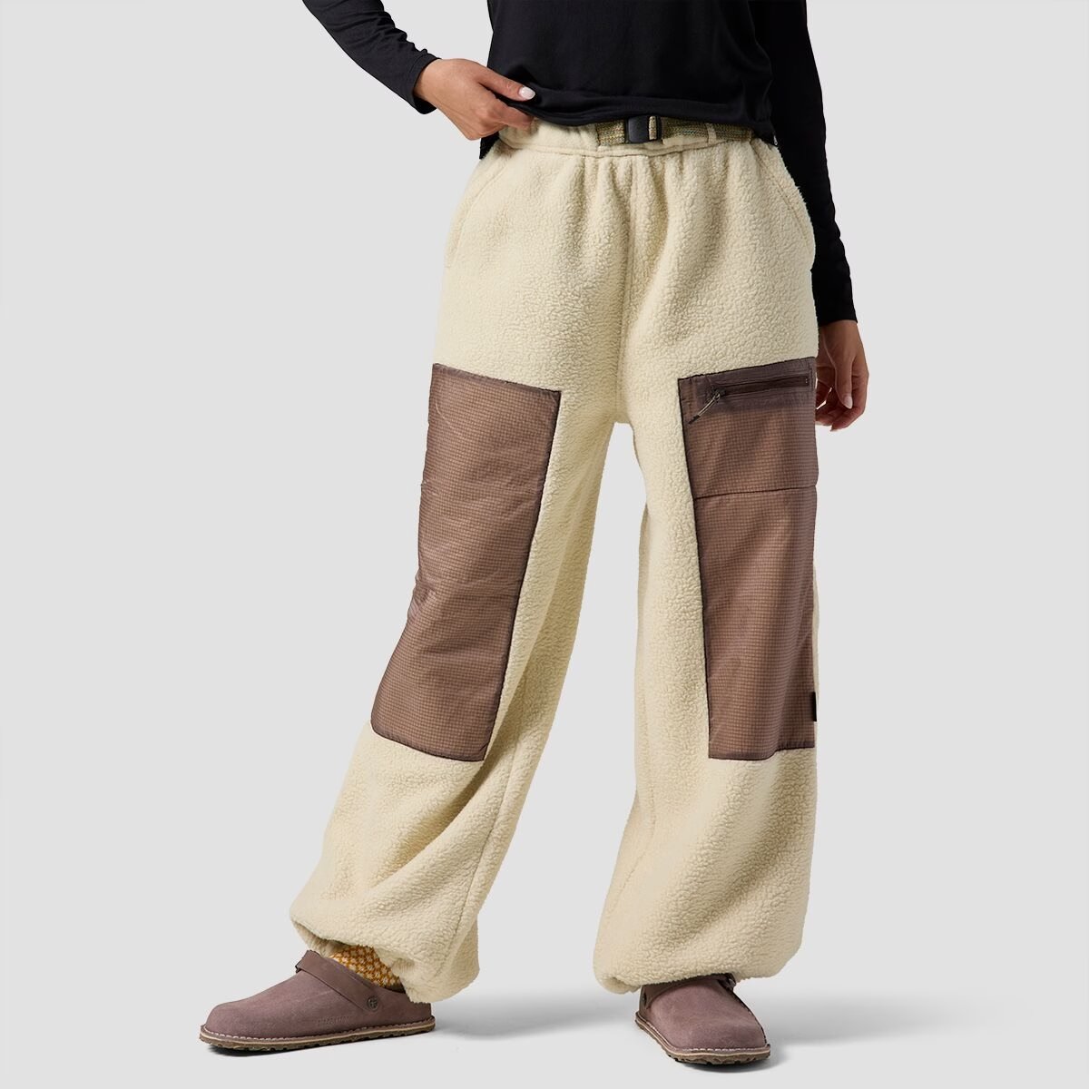 A woman wears tan and brow Wander Pile Fleece pants.