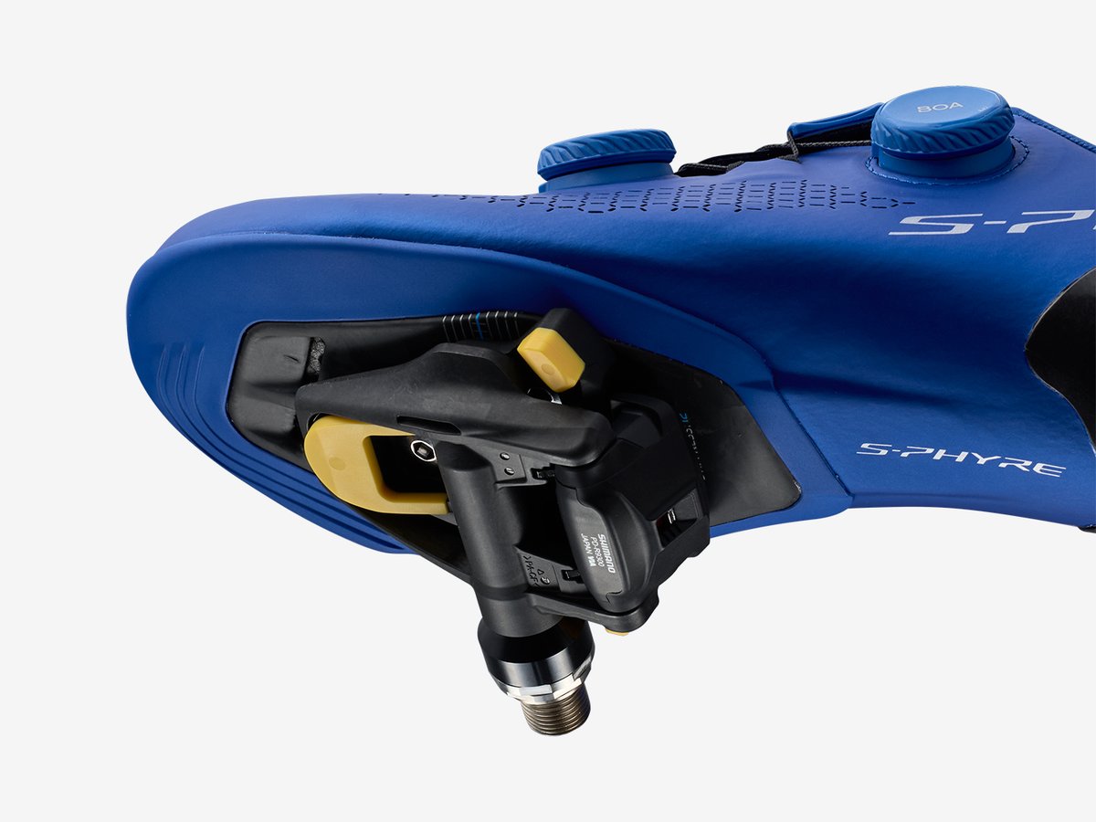 Cutaway render of a blue road shoe sole with cleat and pedal engaged, showing the stack height between foot and axle
