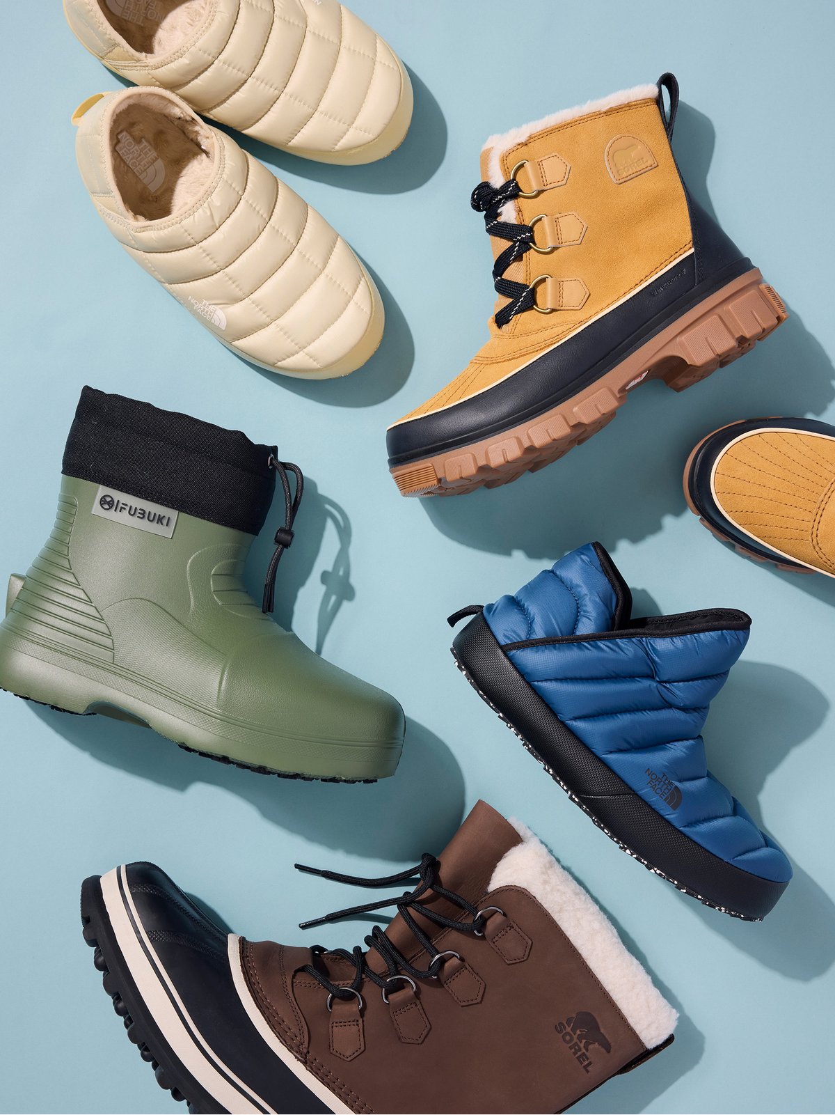 Waterproof boots and puffy slippers laid on a blue background.