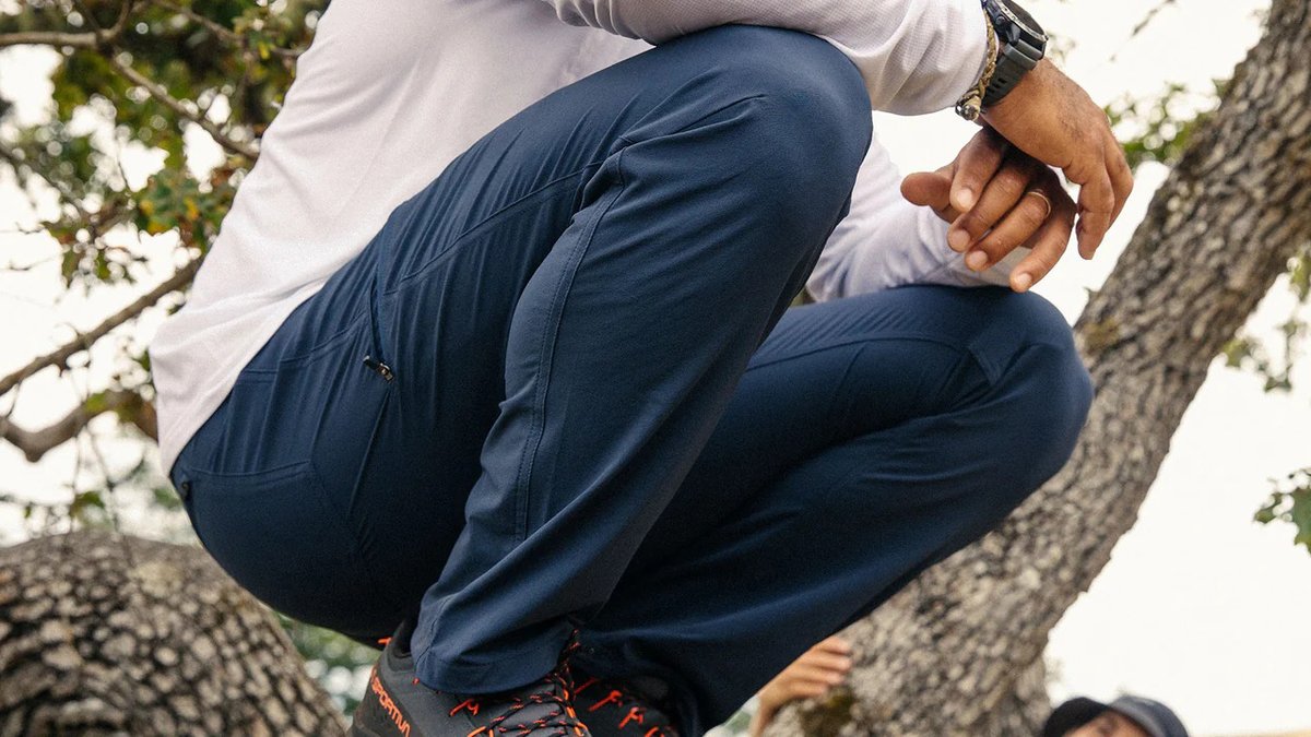 A man wearing Ferrosi pants kneels down, highlighting the mobile stretch of the fabric.