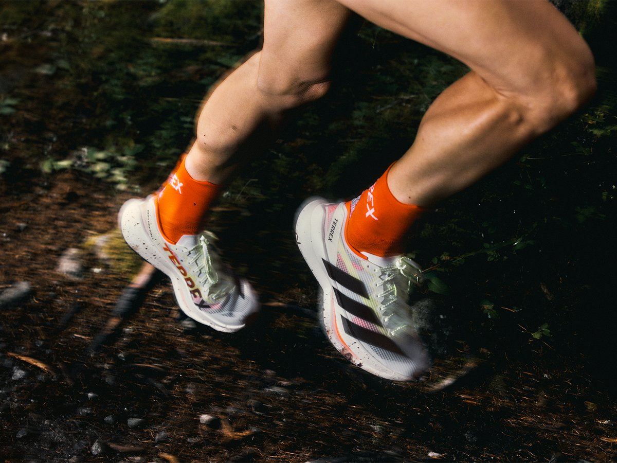 Person running on a dirt trail wearing trail runing shoes and crew socks. 