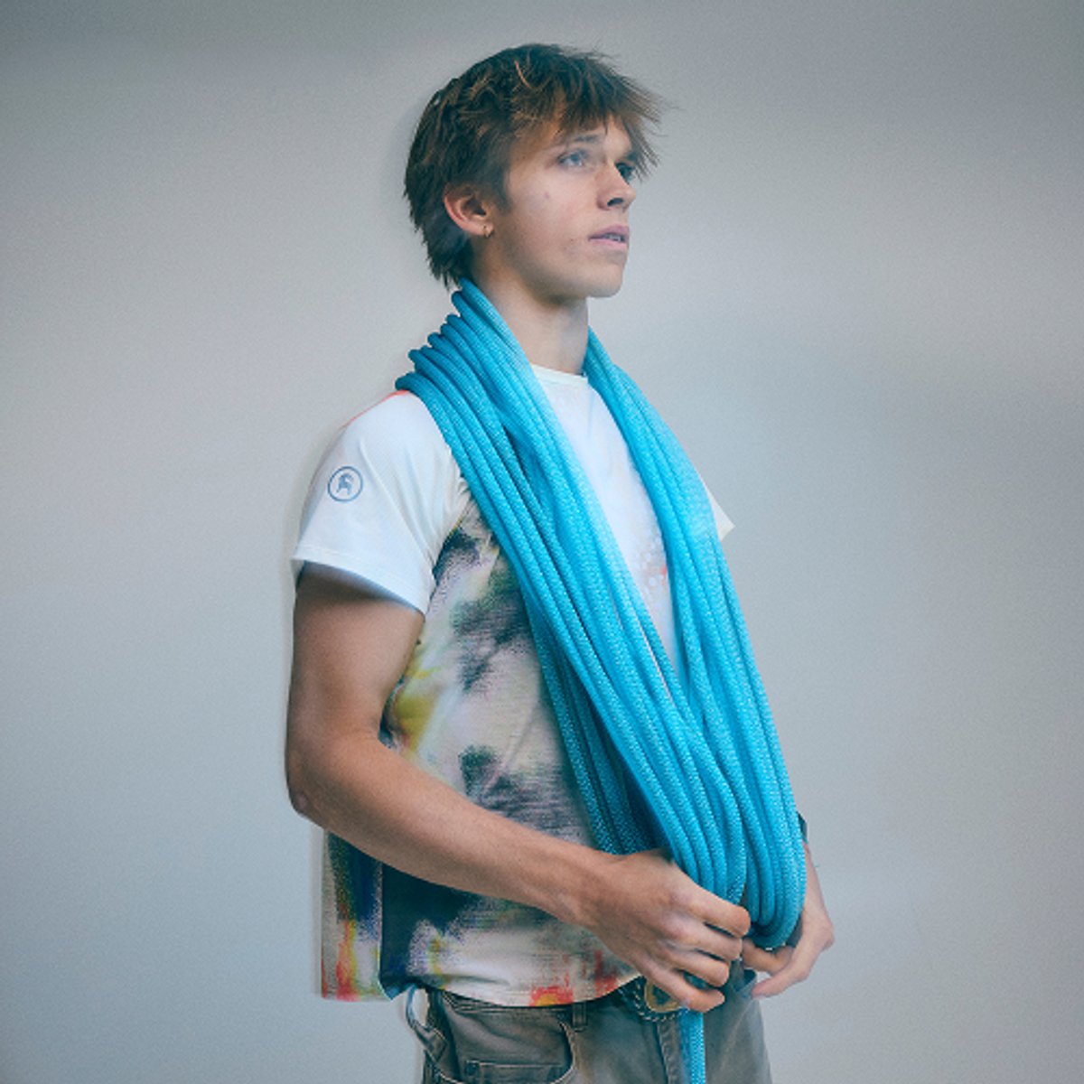 Climber Brayden Butler, a young adult man with straight brown hair, with a climbing rope draped over his shoulders.