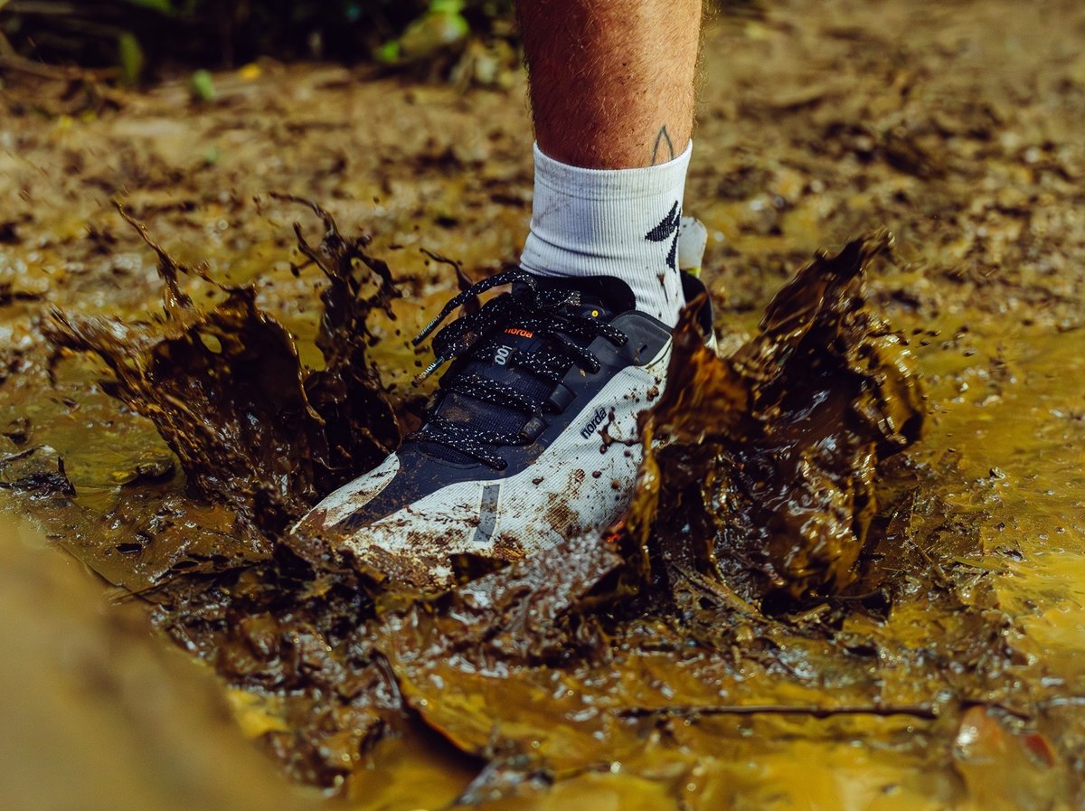 A shoe splashes in muddy water.