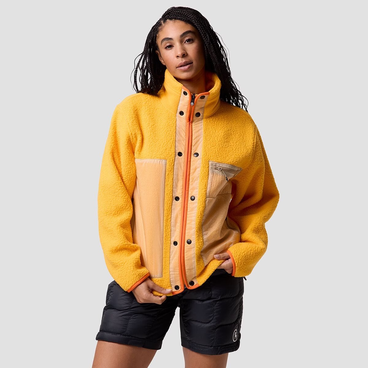 A woman wears a yellow Wander Pile-Fleece jacket.