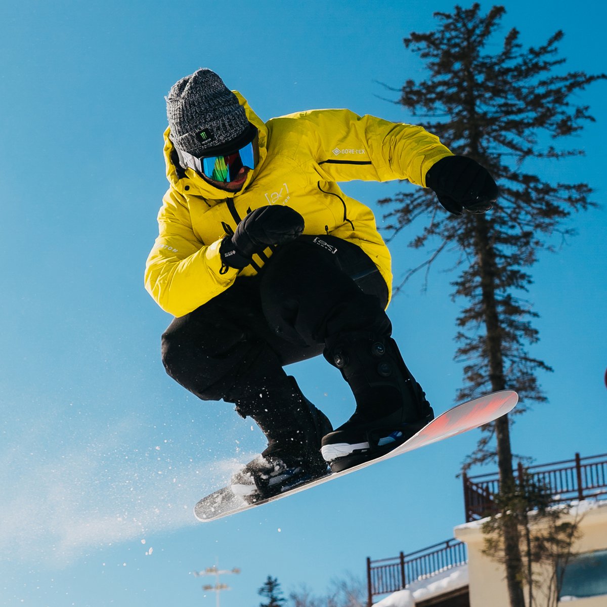 A person in a yellow jacket is snowboarding.