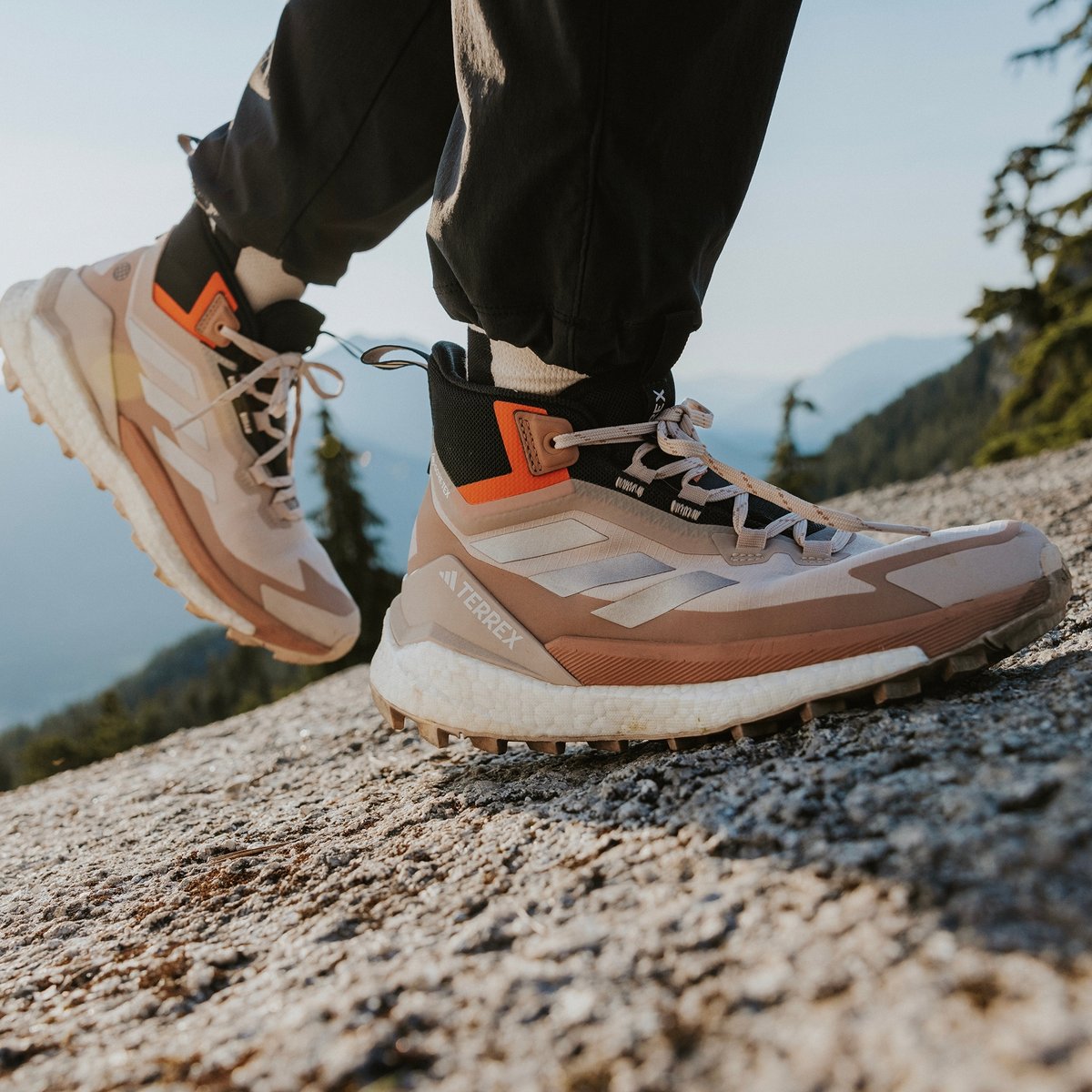 Closeup of brown and white adidas TERREX hiking shoes walking on a gravel path.