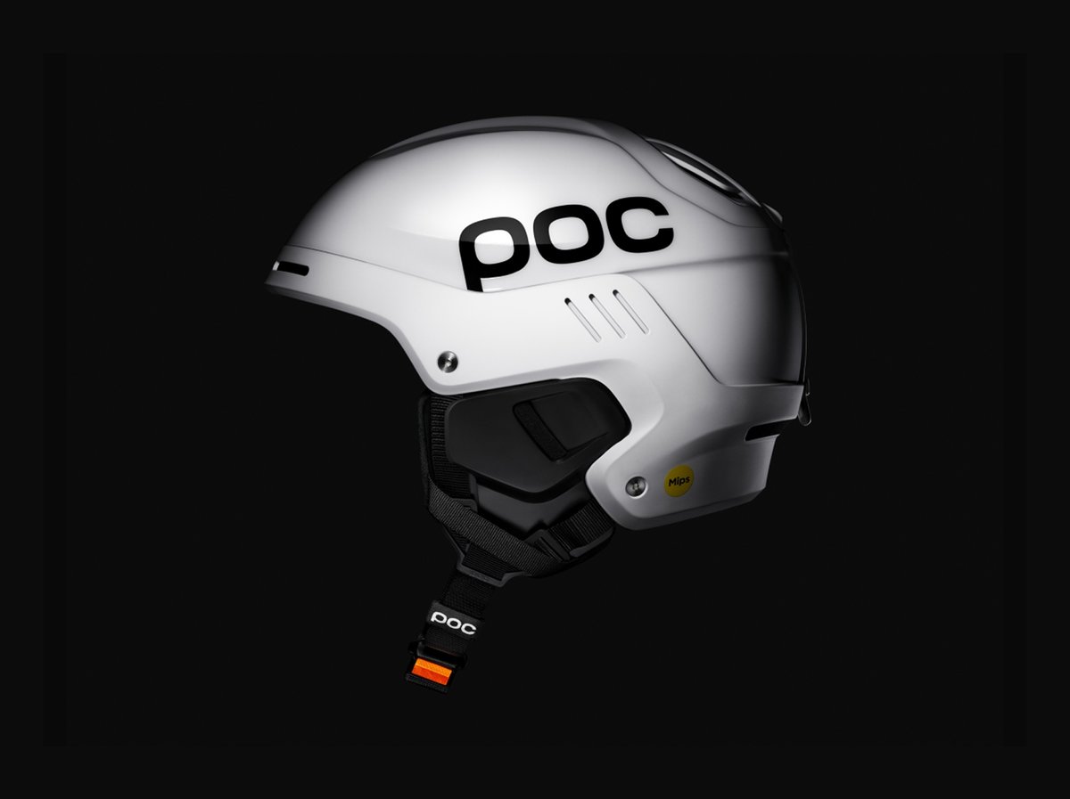 White POC ski helmet in side profile on a black background, with a black chin strap and an orange buckle.