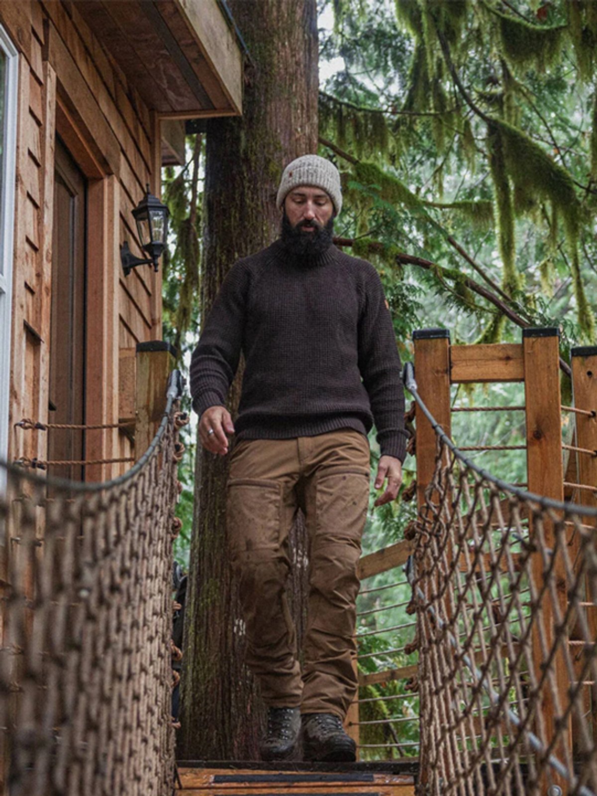A man walks across a rope suspension bridge.