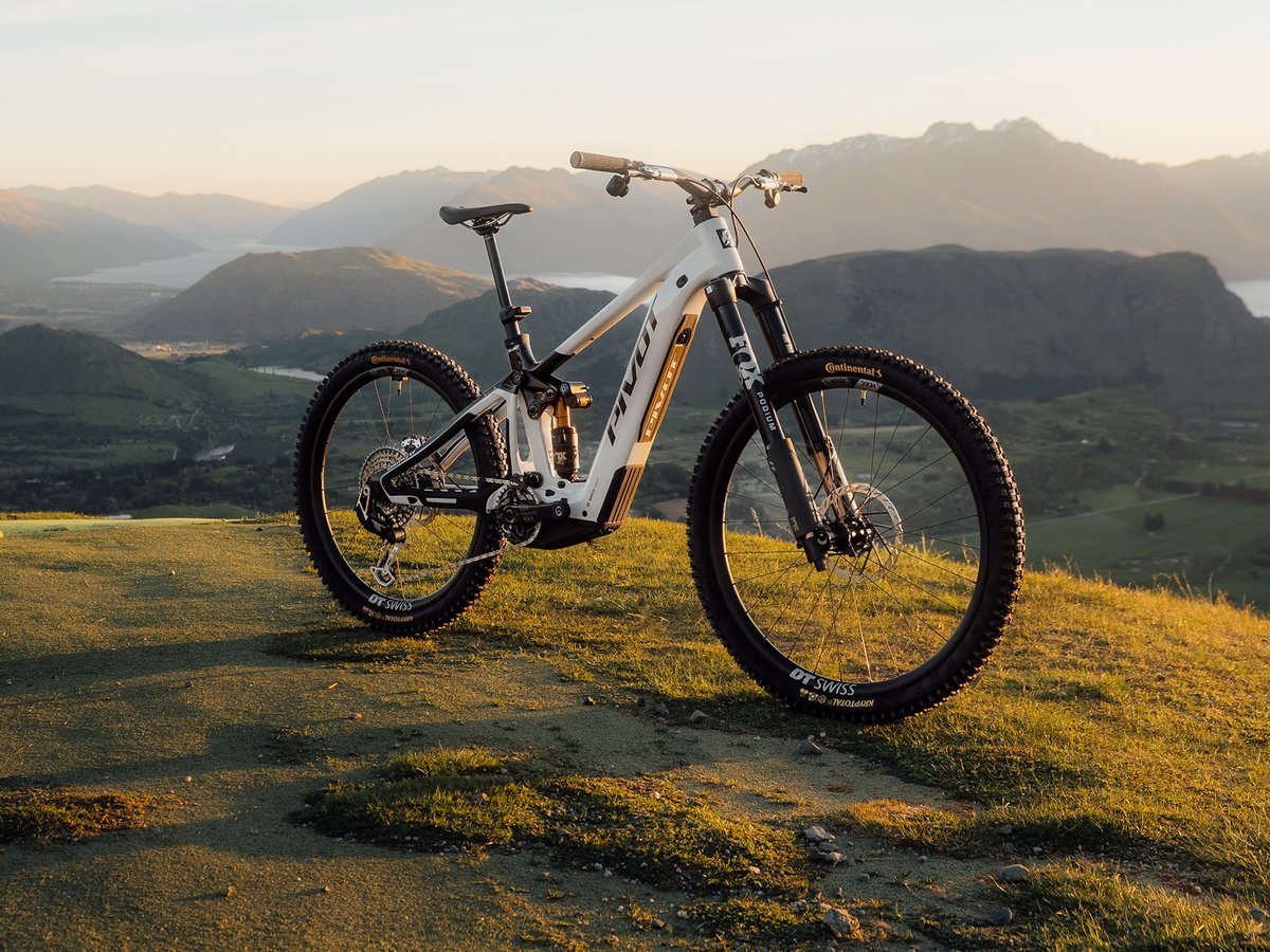 A Pivot eMTB on a grassy knoll at sunset.