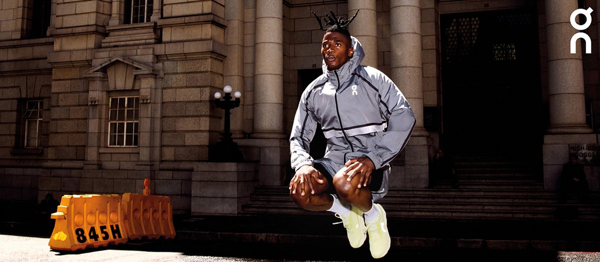 Man jumping in the air in an urban environment wearing bright yellow Cloudmonster 3 shoes.