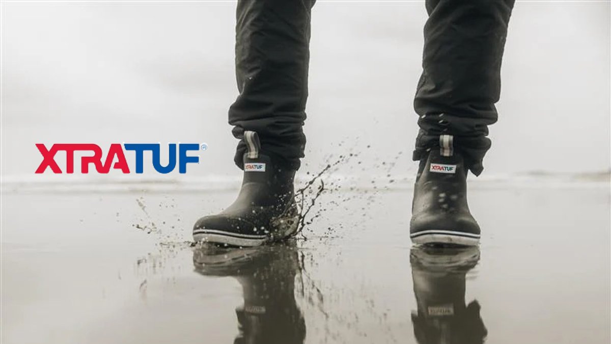 Waterproof black Xtratuf boots splashing through shallow water, showcasing durable outdoor footwear for wet weather conditions.
