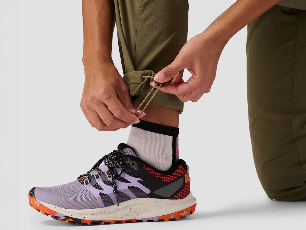 Detail of person wearing ripstop pants tightening ankle hem cinch.