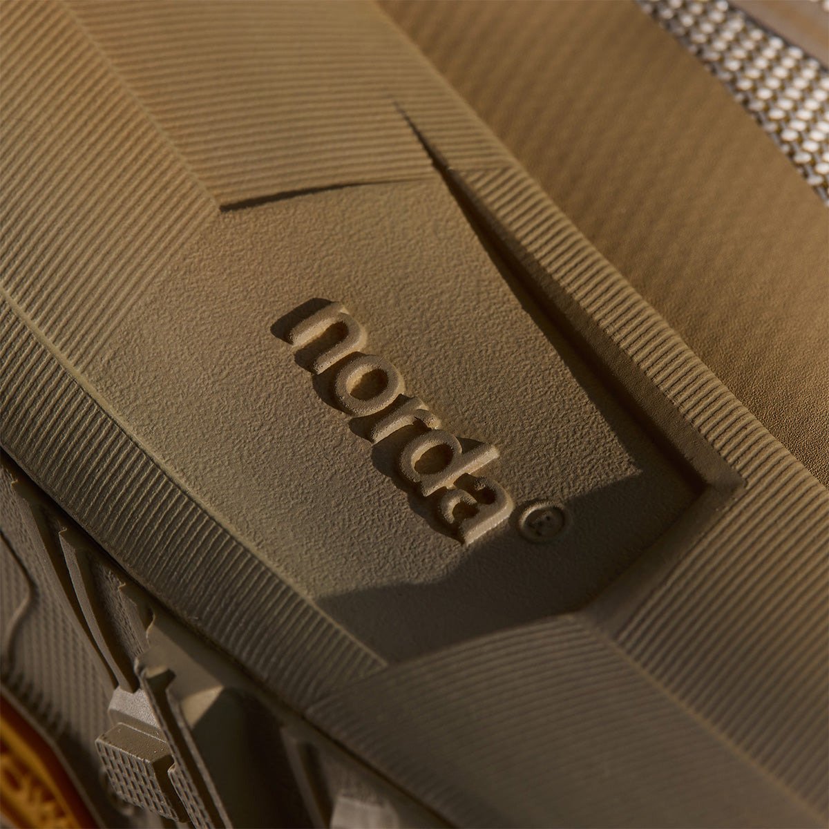 Close-up of the tan Norda midsole showing embossed norda wordmark and ribbed foam texture detail.