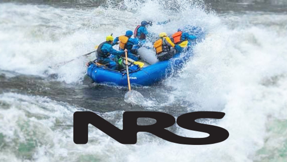 A group of whitewater rafters navigate through turbulent rapids in a blue inflatable raft while wearing yellow and blue safety gear and helmets.