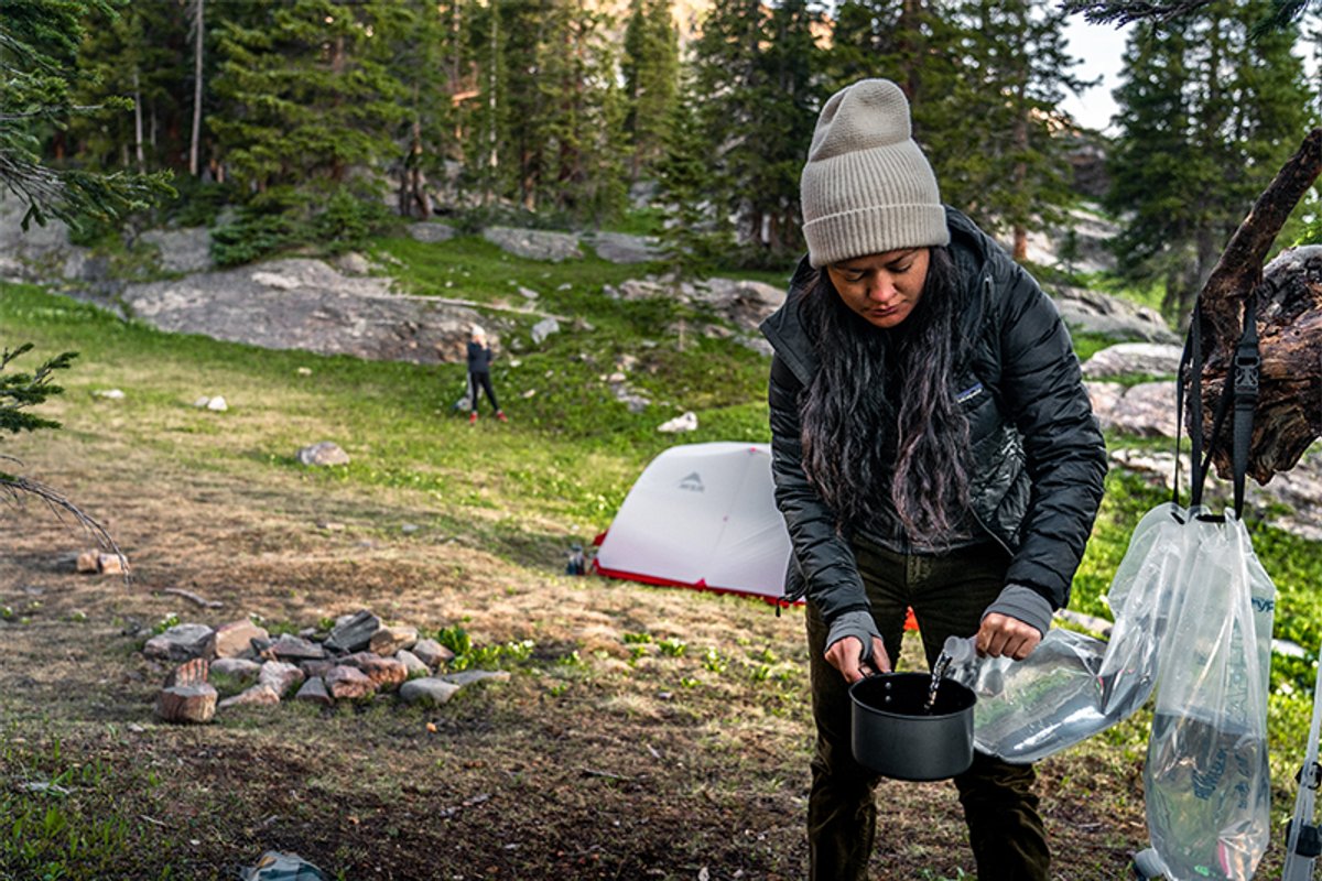 A woman fills up a cooking pot with clean water from the Platypus Gravity Works.