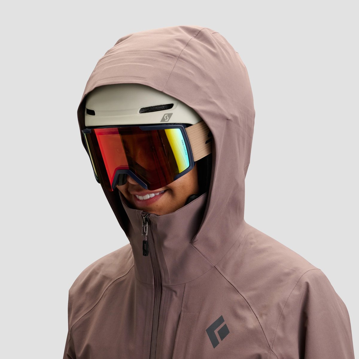 A woman wears the Black Diamond Recon Insulated jacket with a helmet on, highlighting the helmet compatability.
