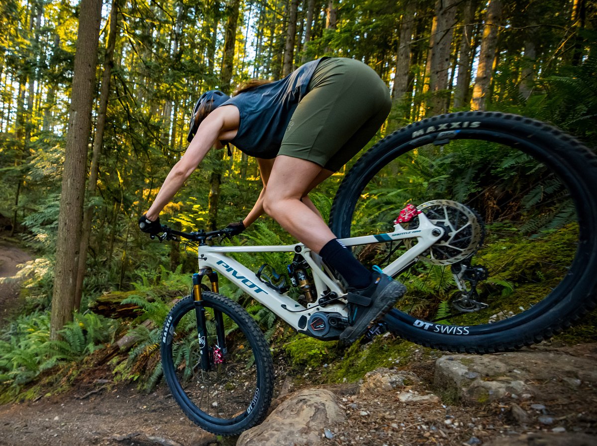 A downhill mountain biker does a steep drop on an electric mountain bike.