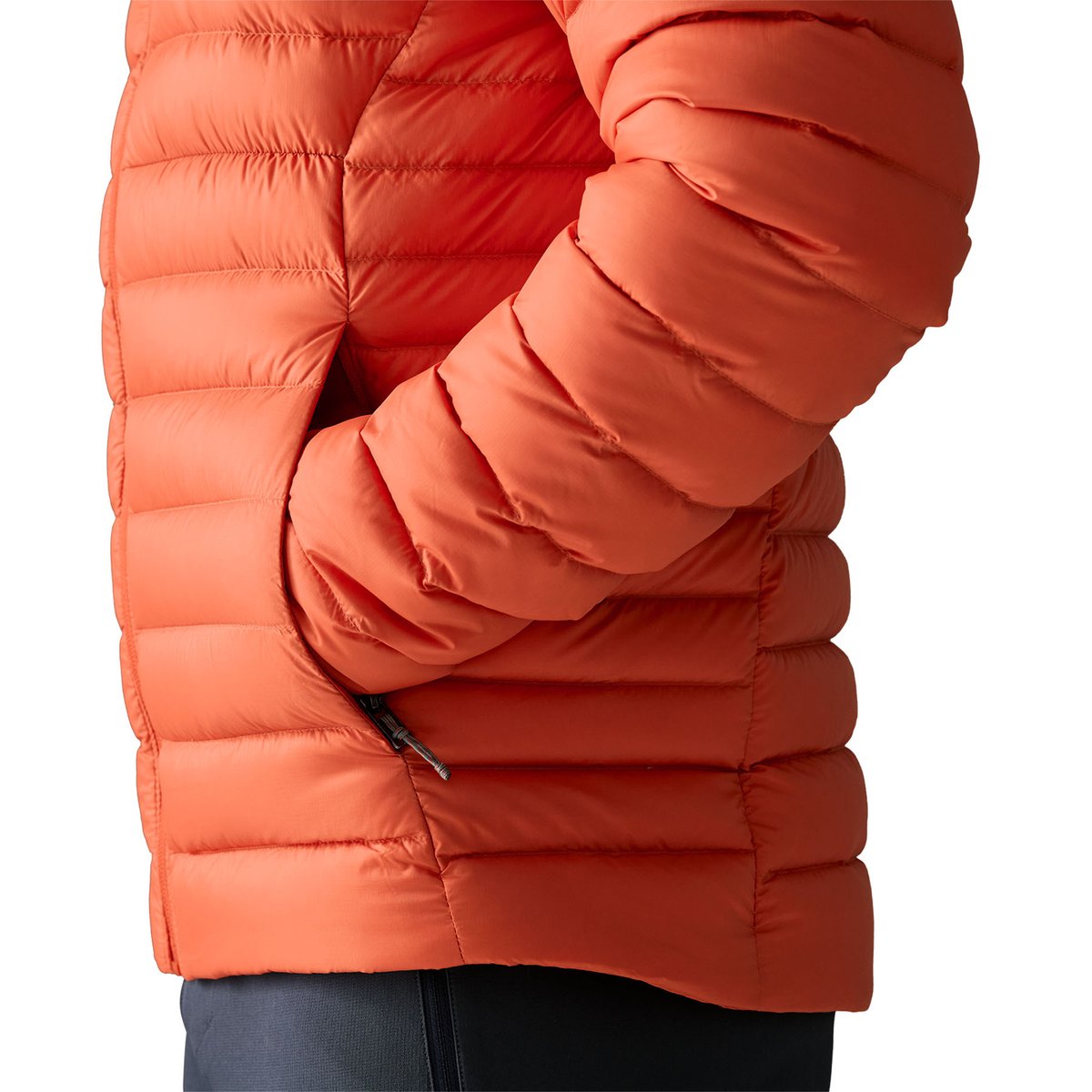 A side view of a person putting their hands in the handwarmer pockets of the Patagonia Down Sweater Jacket. 