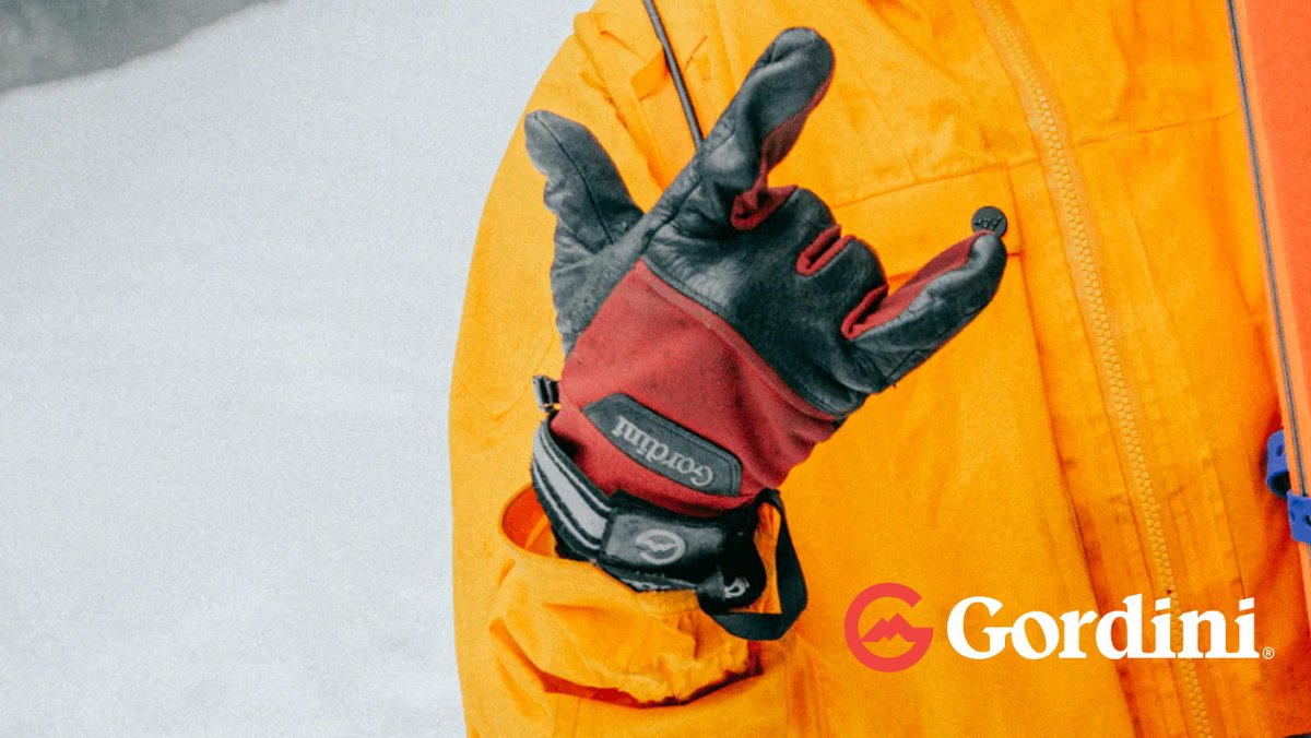 Gordini winter gloves in red and black displayed on a bright yellow jacket sleeve in snowy conditions.