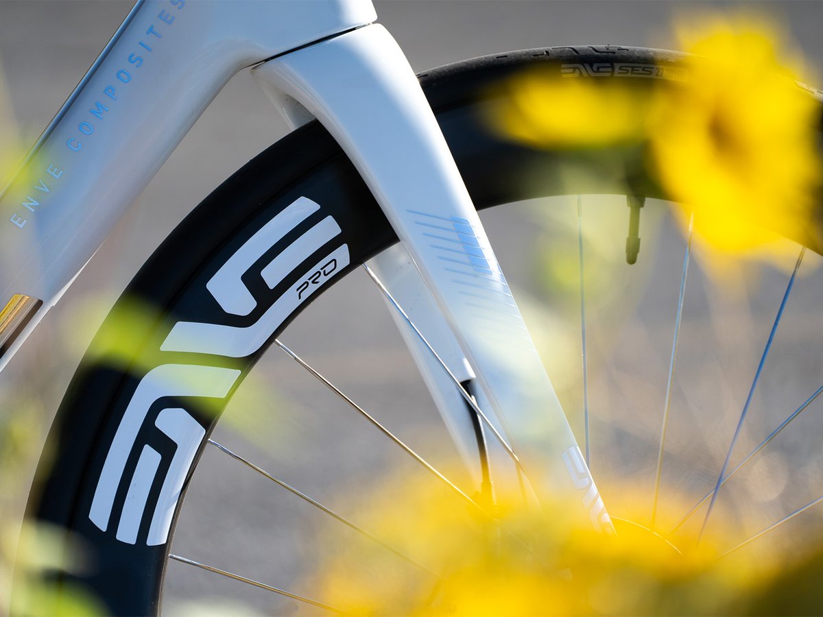 Close-up of the ENVE SES 6.7 PRO wheel and fork, showing the carbon rim and ENVE Composites branding, framed by sunflowers.