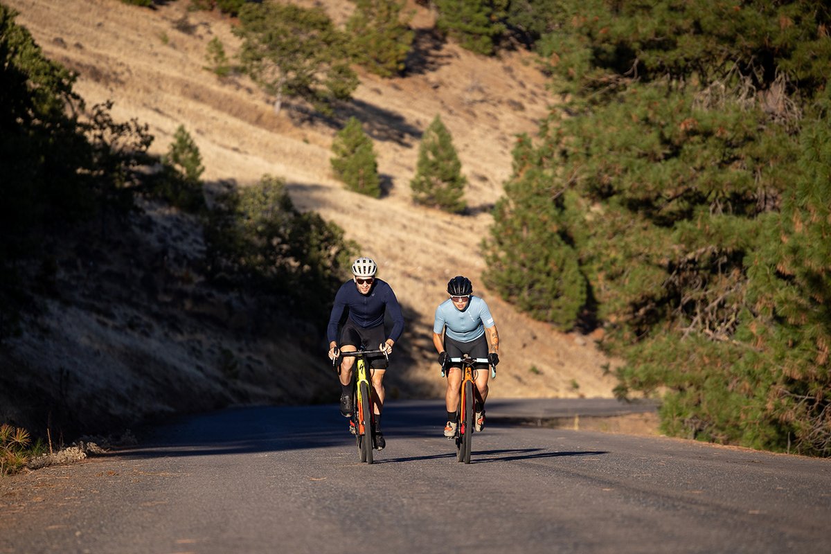 Two cycllicsts riding up a paved road.