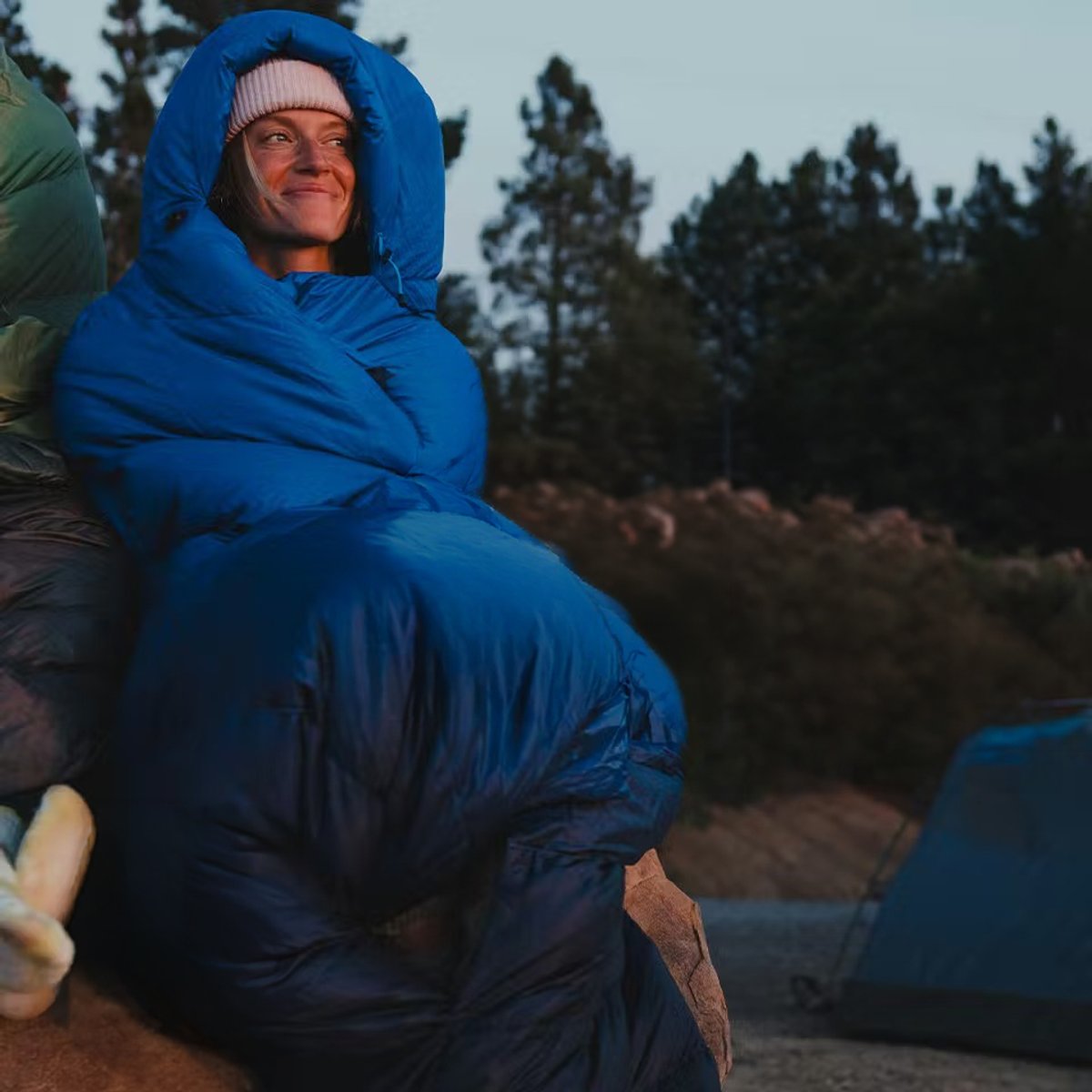 A woman leans against a rock, with the Marmot Wraptor bundled around her head and body.