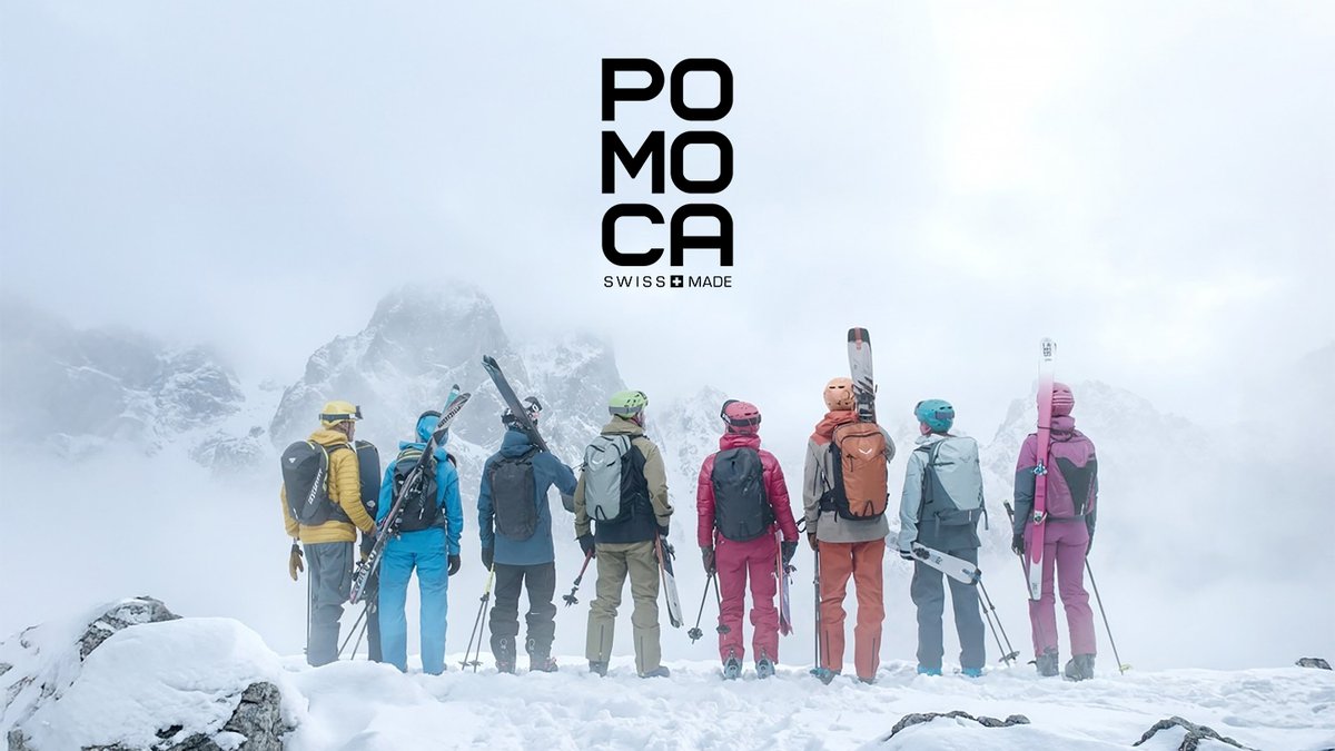 A group of skiers and snowboarders wearing colorful POMOCA Swiss-made winter gear and backpacks standing together in snowy Alpine mountains.