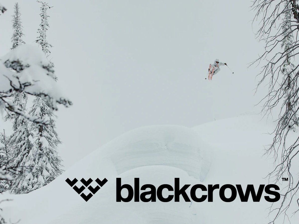 Skier launching off a snow-covered ridge in an alpine winter landscape with Blackcrows logo overlay.