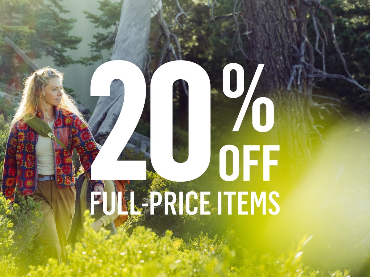 Woman hiking through sun-dappled alpine terrain in a bold floral fleece. Text reads: 20% off full-price items.