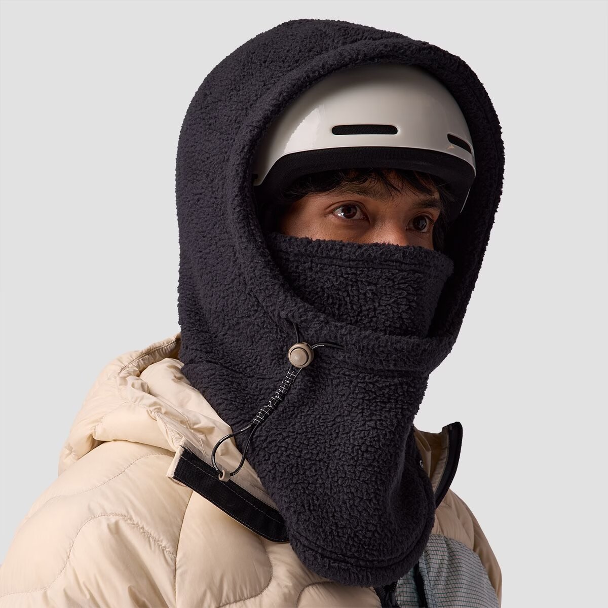 A person wears the BGA Wander Fleece Hood over a helmet 
