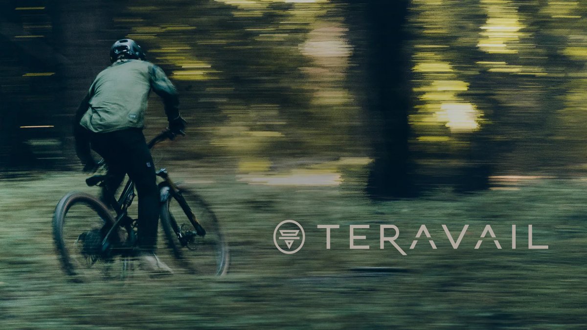 Mountain biker wearing protective helmet and Teravail gear riding fast through forested trail with motion blur effect.