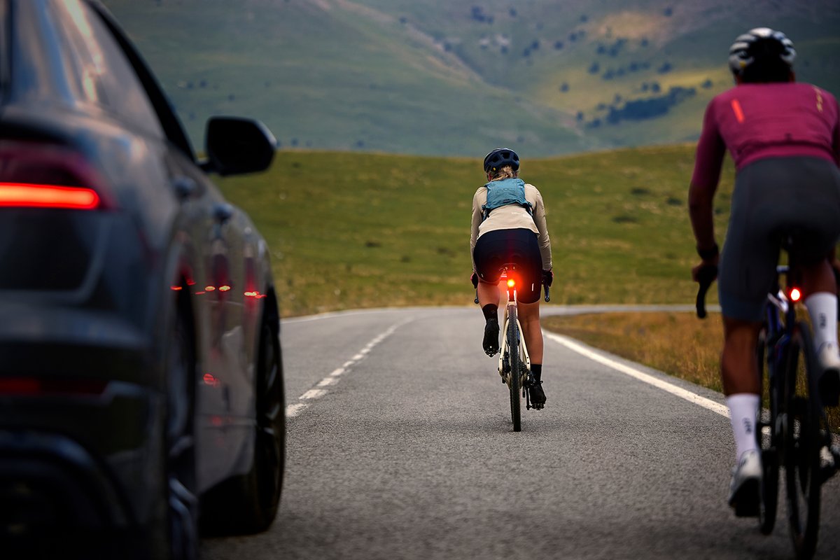 Cyclists riding on open road with bright rear bike lights for visibility