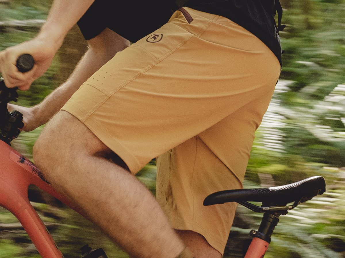 Crop shot of person pedaling uphill on a mountain bike wearing Slickrock shorts.