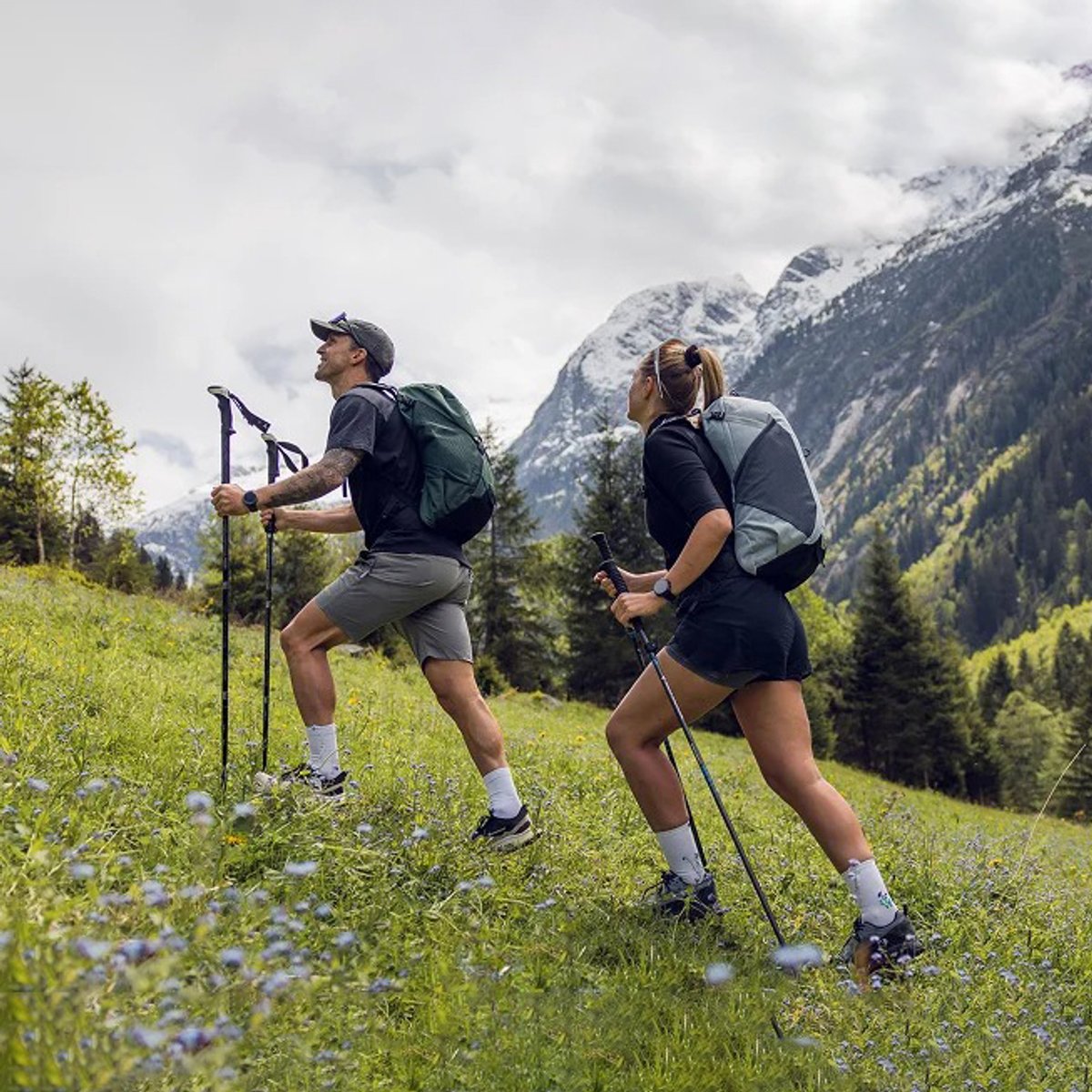 Two hikers wearing Osprey packs hike along an alpine ridge.