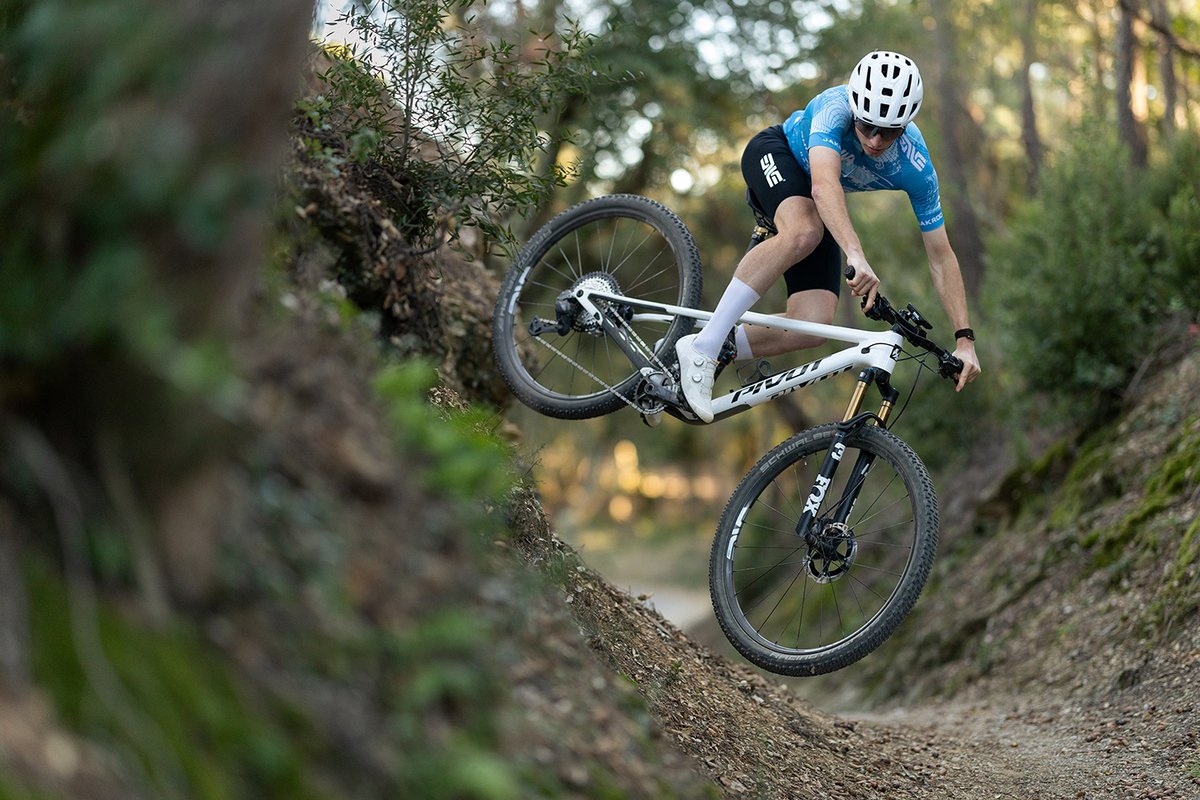 Rider cornering the Pivot Mach 4 SL carbon XC mountain bike on forest singletrack