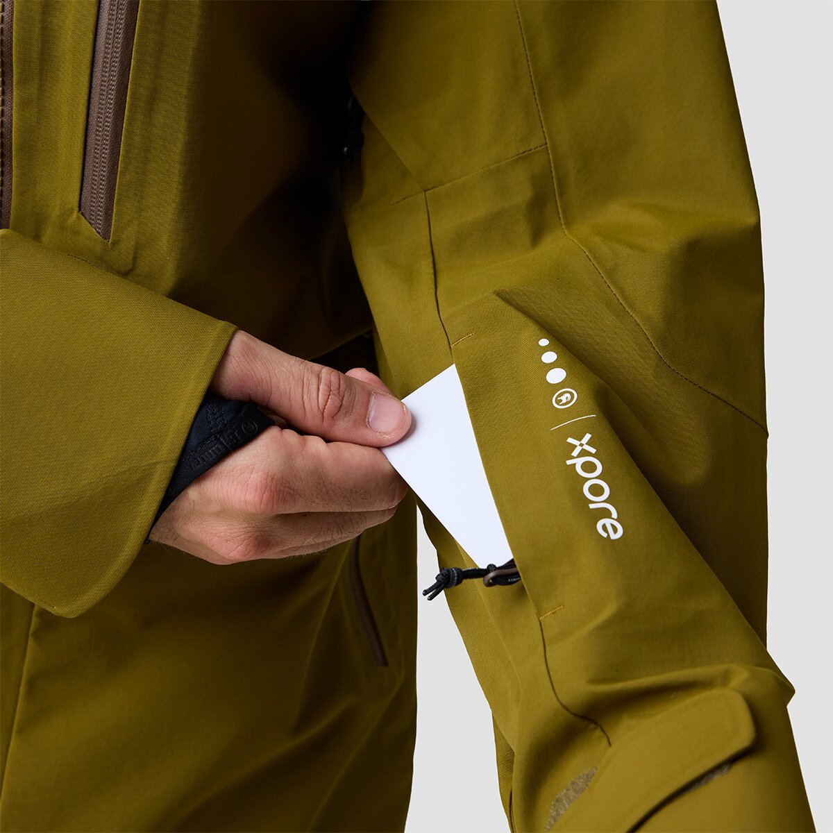 Person removing ski pass from zippered sleeve pocket of Cottonwoods ski jacket.