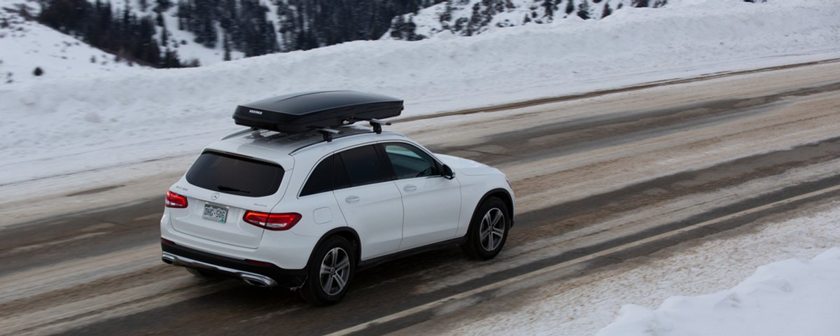 Yakima GrandTour roof cargo box mounted on SUV driving through snowy mountain road
