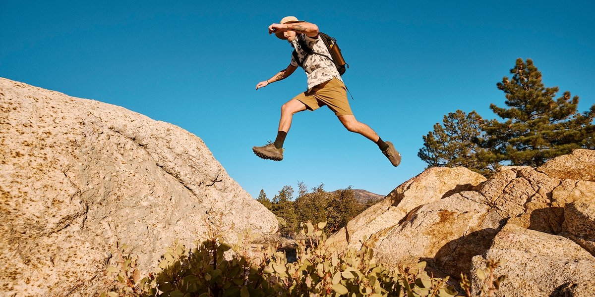 A hiker leaps between two rocks.