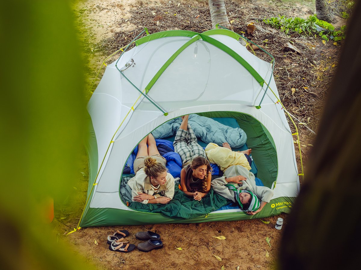 Three women lay inside a tent with its door open.