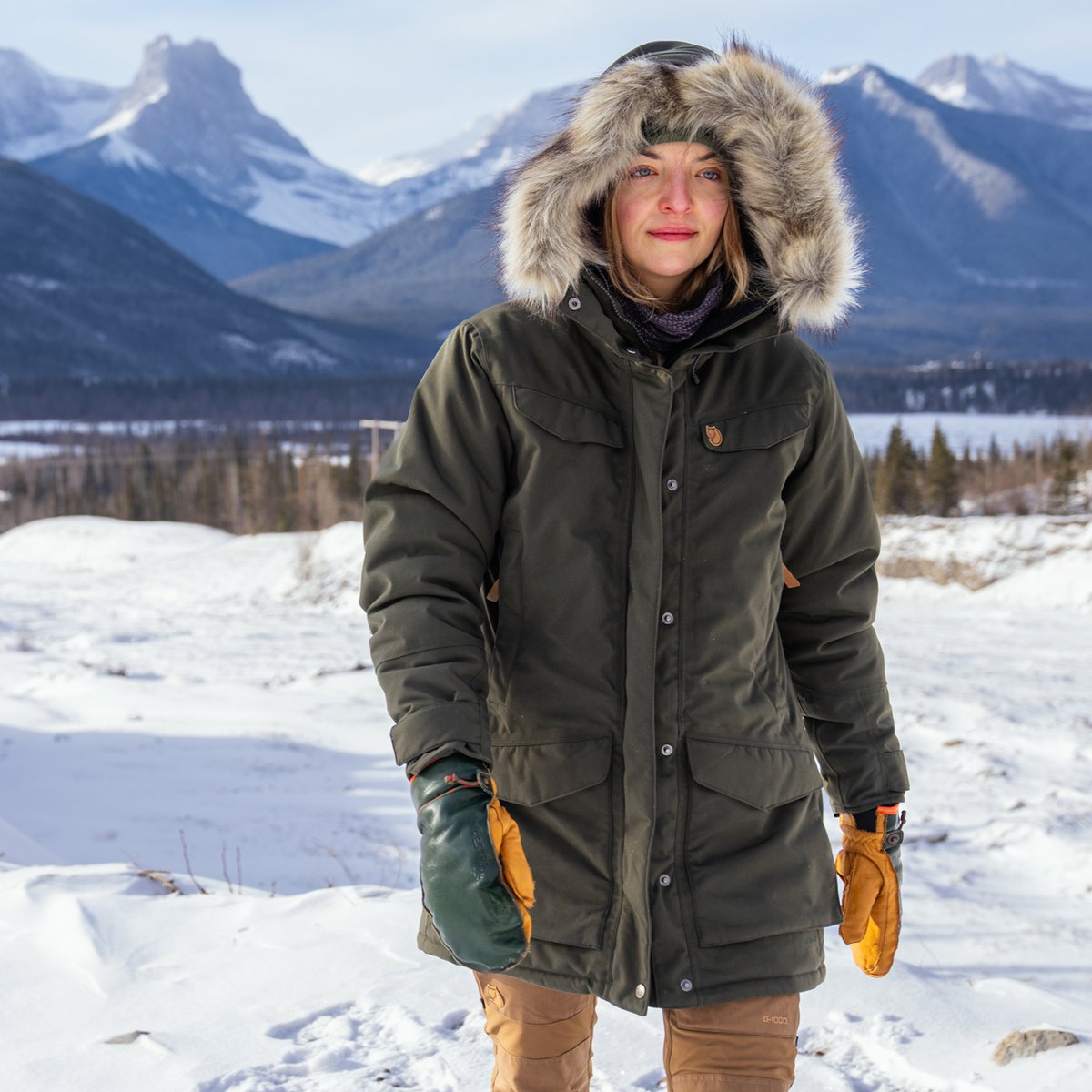 A woman walks outside in a parka.