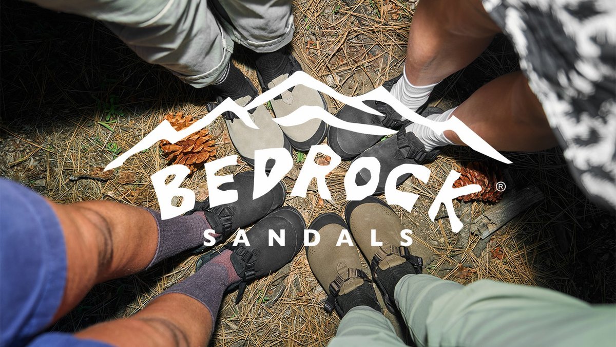 Overhead group shot of five people standing in a circle wearing Bedrock Mountain Clogs in various colorways on pine needle forest floor, Bedrock Sandals logo overlaid