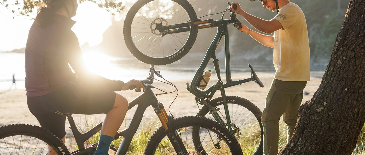 Two riders hanging out on their bikes at a scenic overlook at sunset.