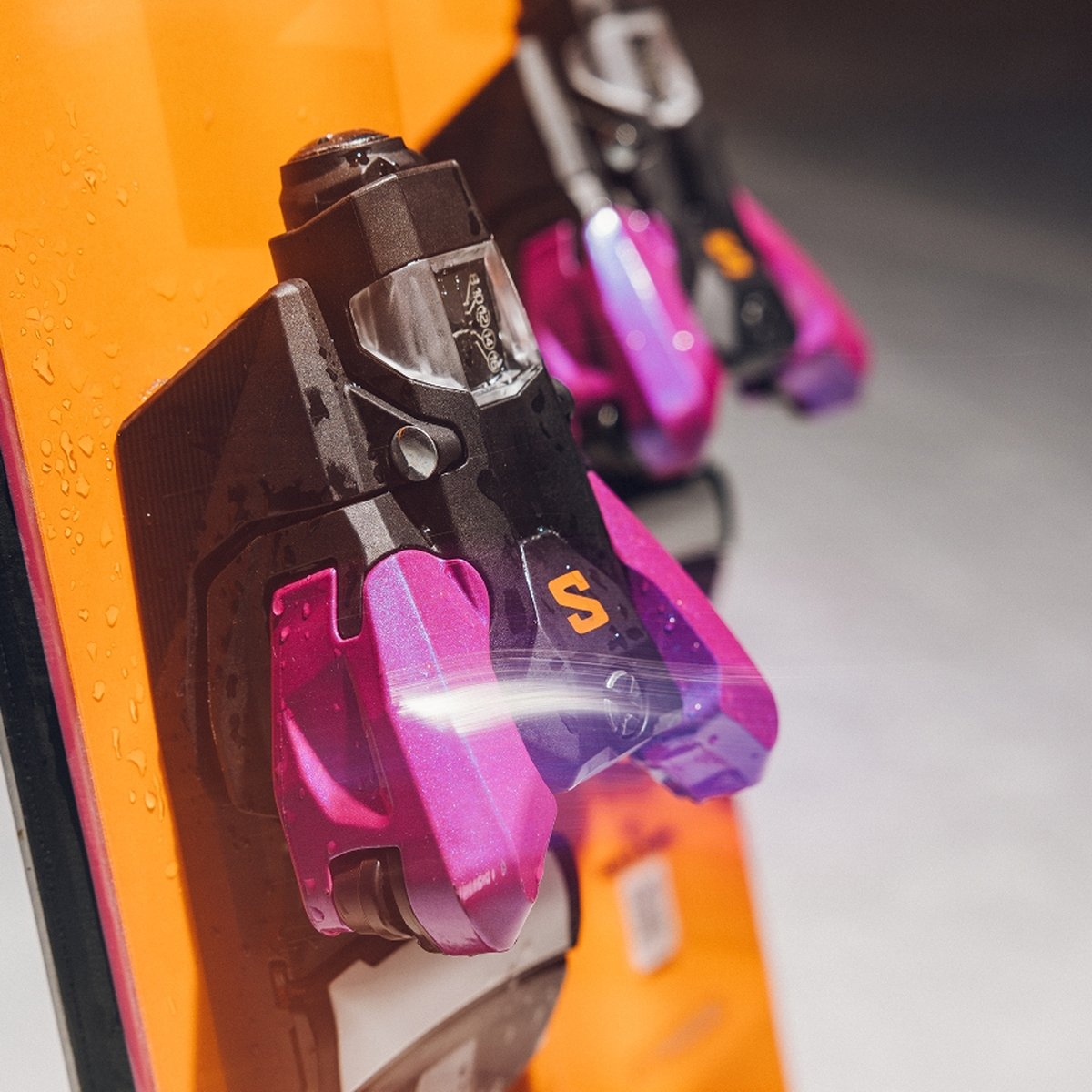Purple bindings are mounted on orange skis.