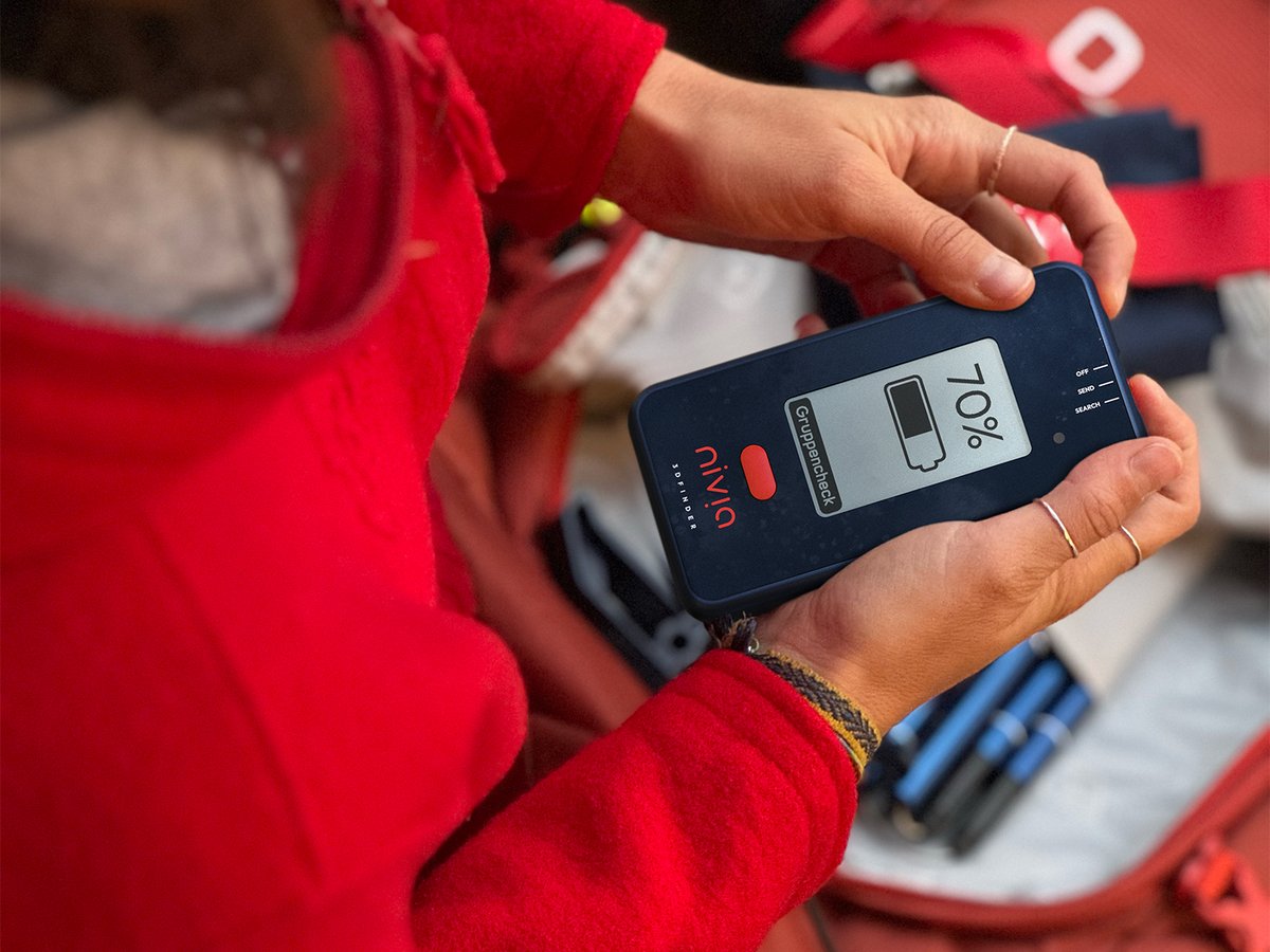 Skier in red checking the battery level on a Nivia 3D Finder.