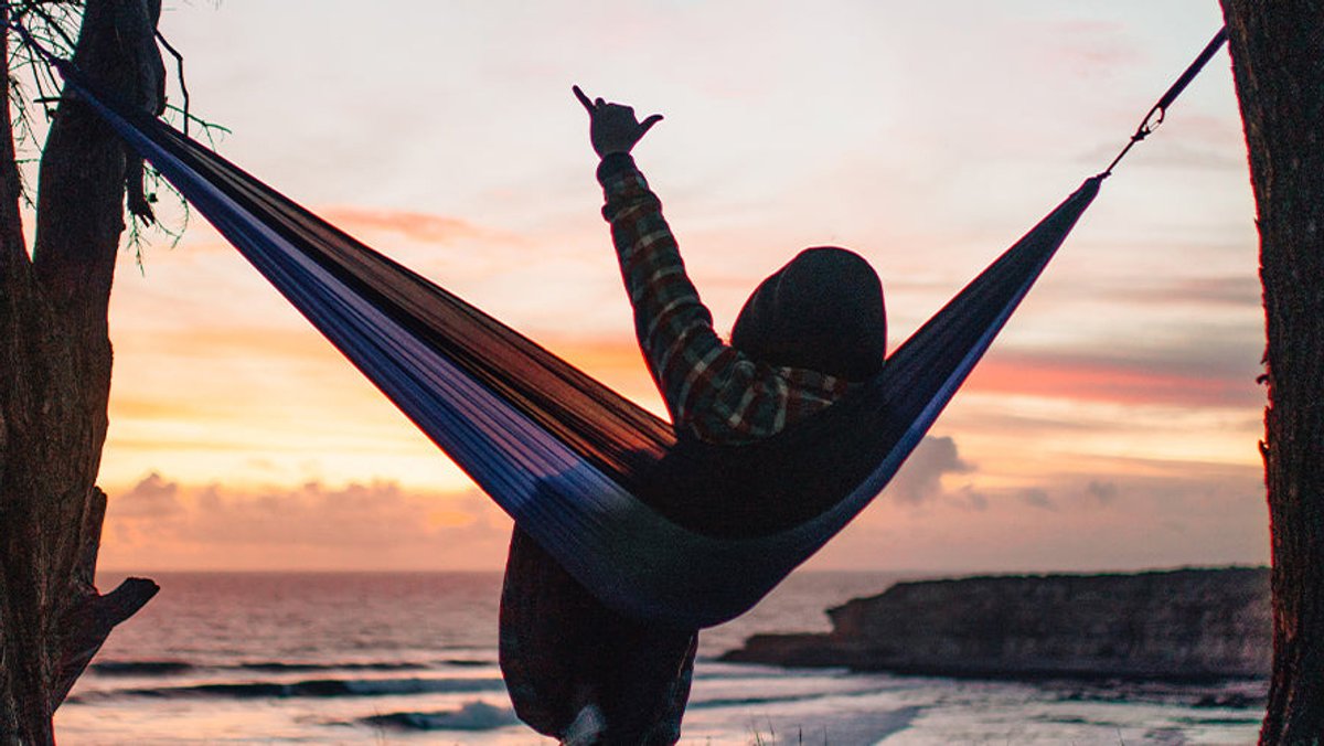 Person hanging out on a Coalatree hammock at the beach